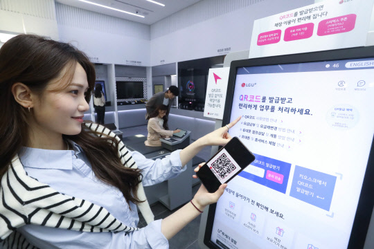 모델이 LG유플러스의 '언택트스토어 1호점' 웰컴보드에서 QR코드를 발급받고 있다. LG유플러스 제공